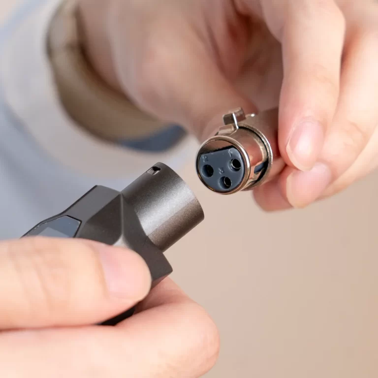 Close-up of hands connecting a round 3-pin electrical connector to a handheld device. ขายราคาพิเศษ