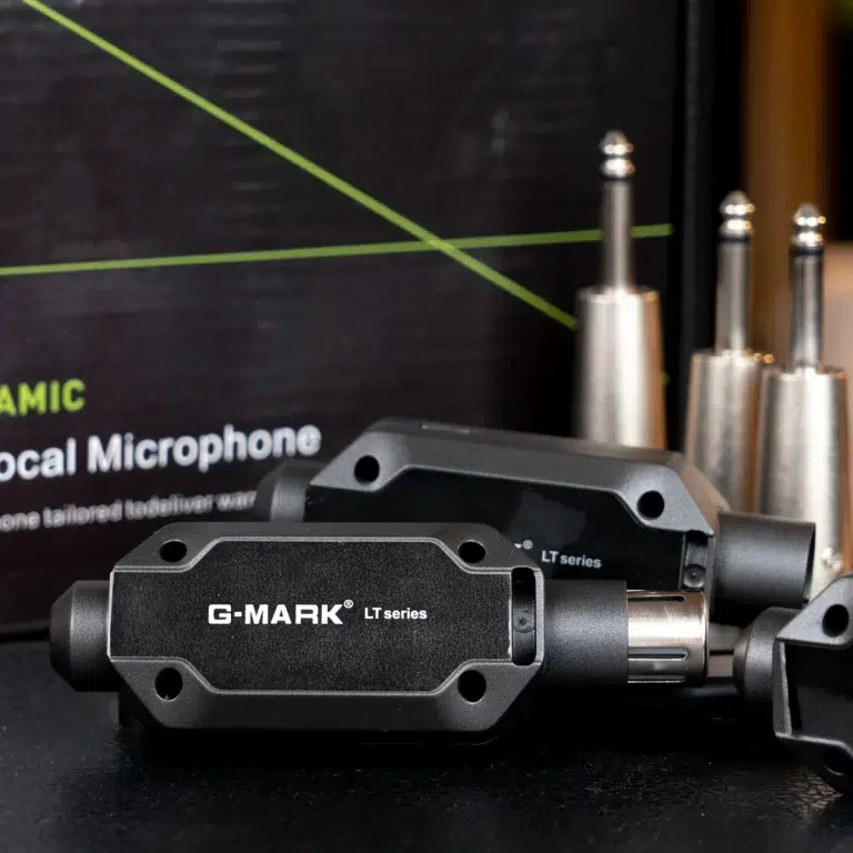 Close-up of G-MARK LT series microphone adapters on a desk with metallic plug connectors in the background. ขายราคาพิเศษ