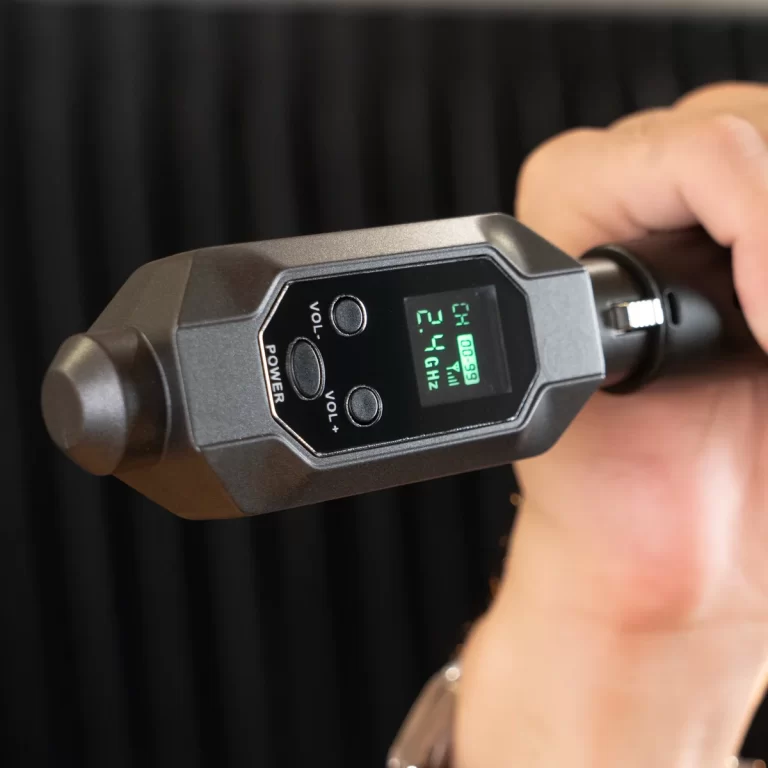 Handheld electronic device with a small green backlit display showing 2.4 GHz; controls labeled VOL+, VOL-, and POWER are visible as a person holds it. ขายราคาพิเศษ