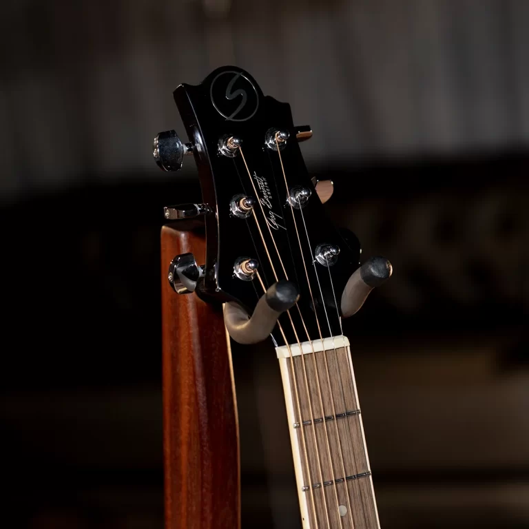 Close-up of a black guitar headstock with six tuning pegs and strings, the neck extending downward on the right. ขายราคาพิเศษ