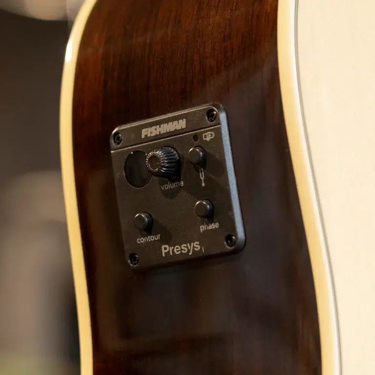 Close-up of a Fishman Presys preamp mounted on the side of a dark wood acoustic guitar, showing volume knob, contour button, phase button, and output indicator. ขายราคาพิเศษ