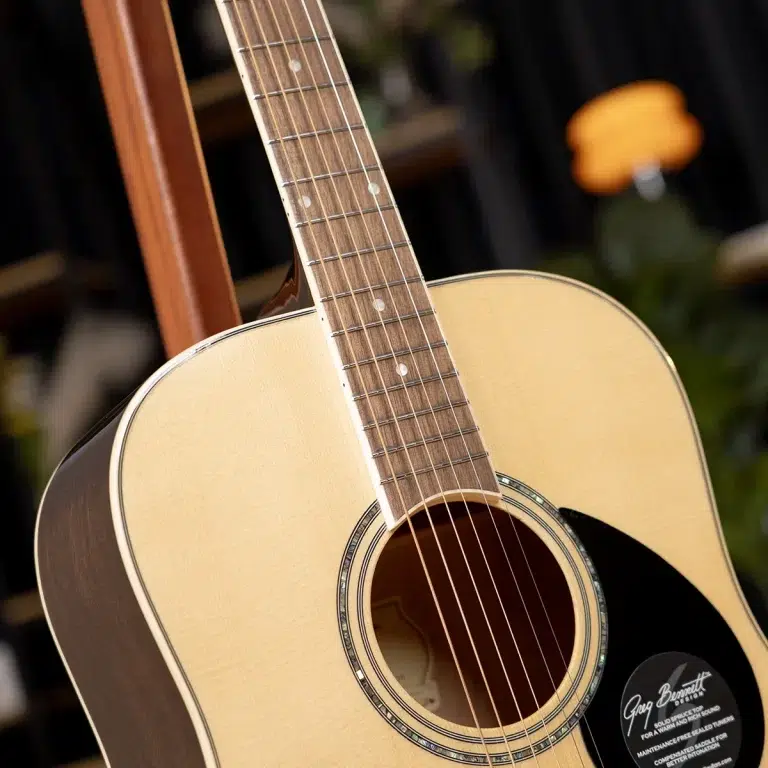 Close-up of an acoustic guitar's neck and light-wood body with strings visible over the soundhole rosette. ขายราคาพิเศษ