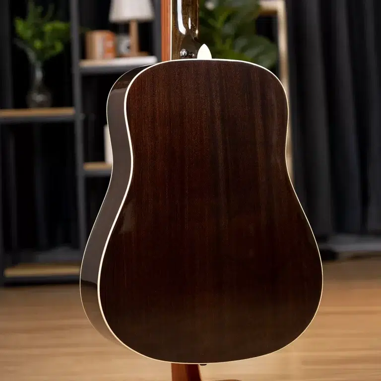 Back of a dark mahogany acoustic guitar with light binding, on a stand in a studio setting ขายราคาพิเศษ