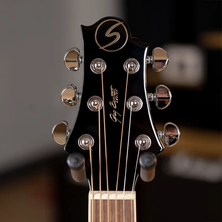 Close-up of a black guitar headstock with six chrome tuning pegs and copper strings, showing the Gibson script logo. ขายราคาพิเศษ