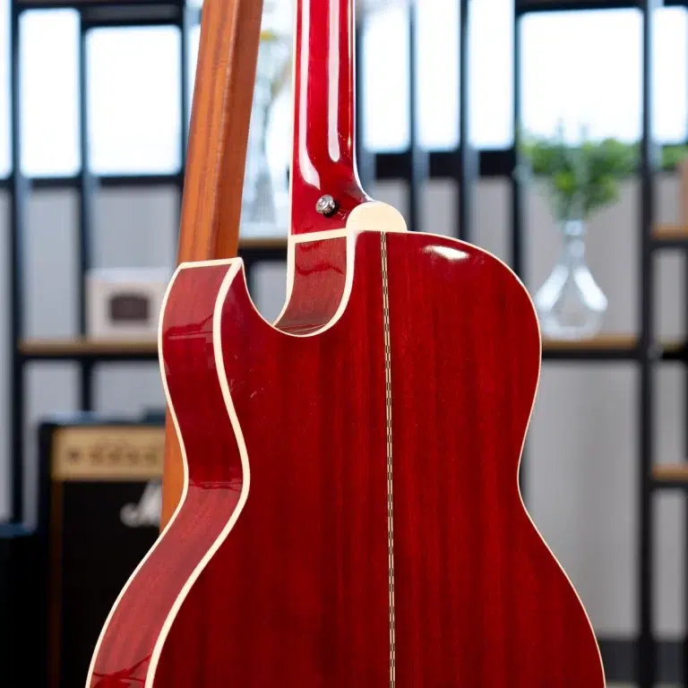 Back view of a red glossy guitar with cream binding, displayed in a music store showroom. ขายราคาพิเศษ
