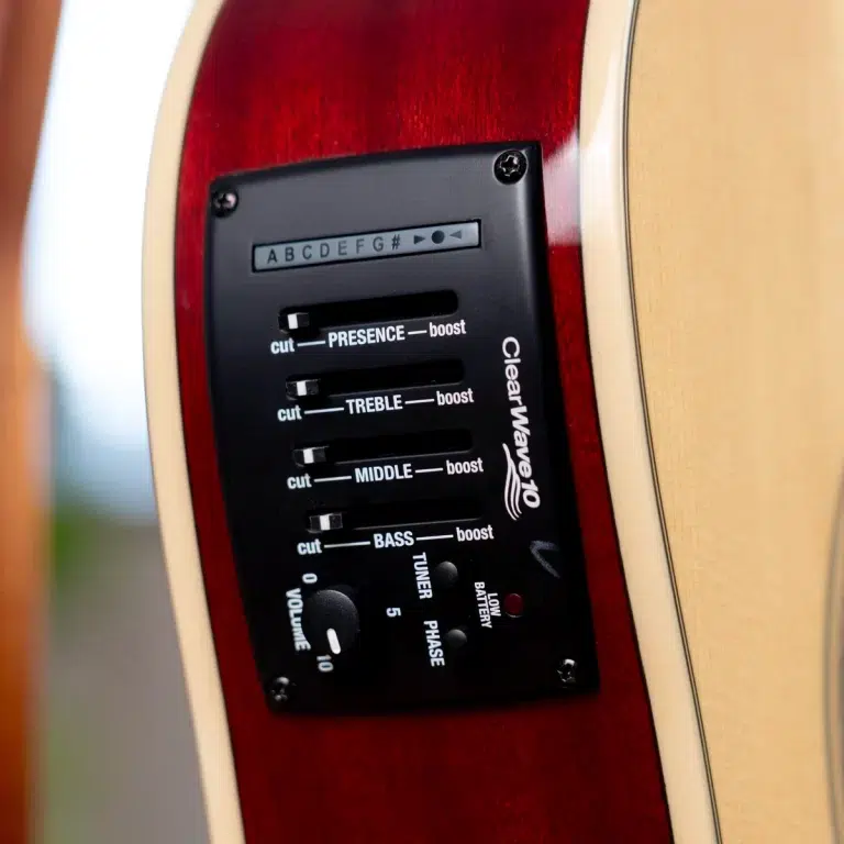 Close-up of an acoustic‑electric guitar's black control panel on a red-burnished body, showing presence, treble, middle, bass boost sliders and volume knob. ขายราคาพิเศษ