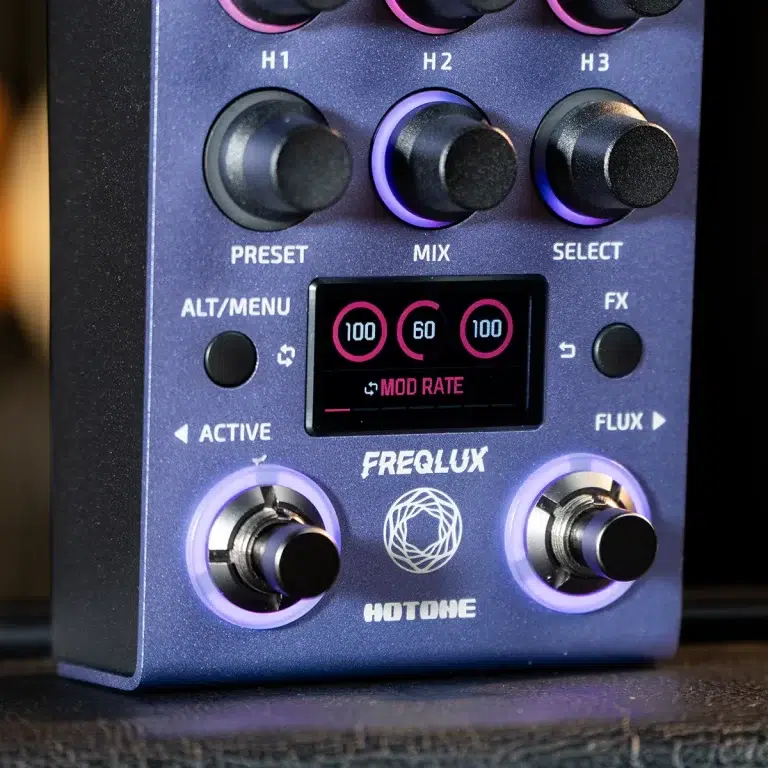 Close-up of a Hotone FREQ LUX guitar effect pedal front panel with colorful knobs, a small display, and illuminated rings around the footswitches. ขายราคาพิเศษ