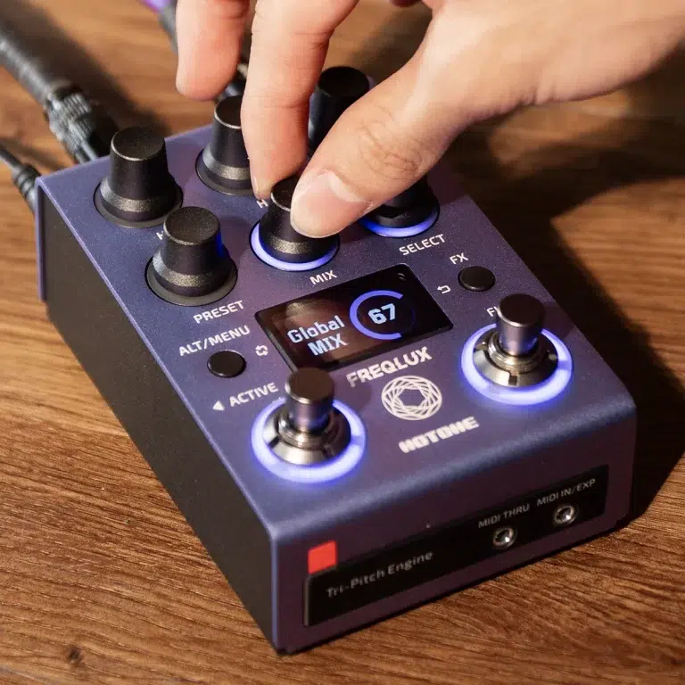 Hand adjusting a knob on a blue MIDI controller with illuminated blue rings around the knobs and a small display showing 'Global Mix'. ขายราคาพิเศษ
