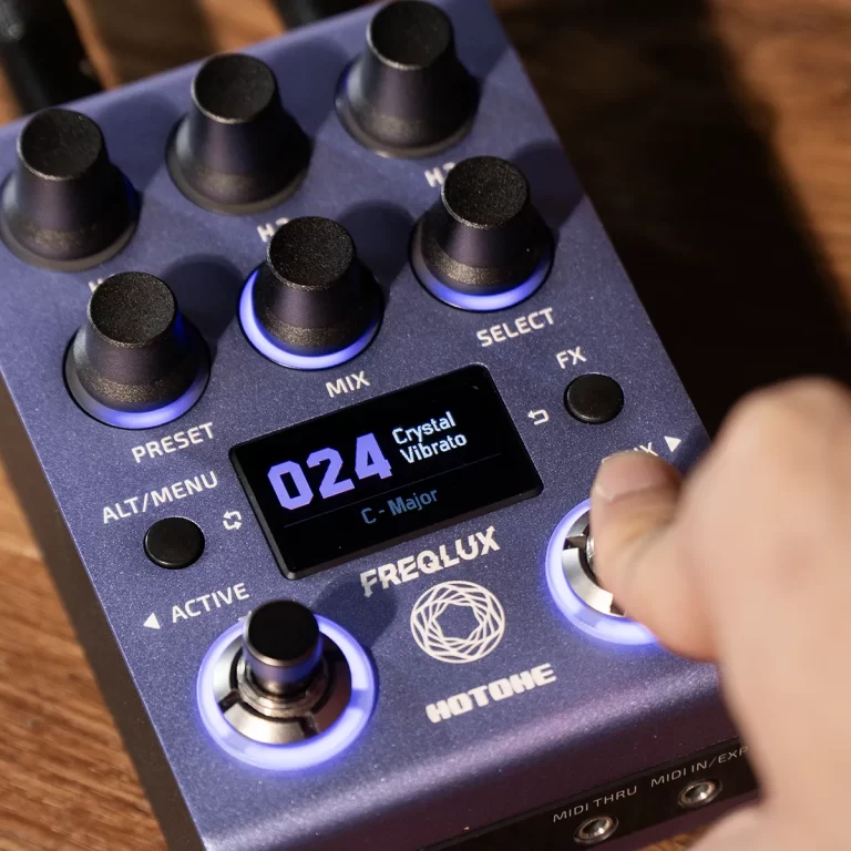 Close-up of a blue Freqlux Hotoke effect pedal with illuminated knobs and a small LCD showing '024 Crystal Vibrato' in C-Major. ขายราคาพิเศษ