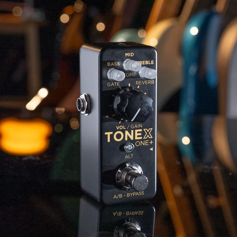 Guitar effects pedal labeled TONEX ONE+ with knobs for Bass, Mid, Treble, and Gain, plus an A/B/BYPASS switch on a black faceplate at a dark studio setting ขายราคาพิเศษ