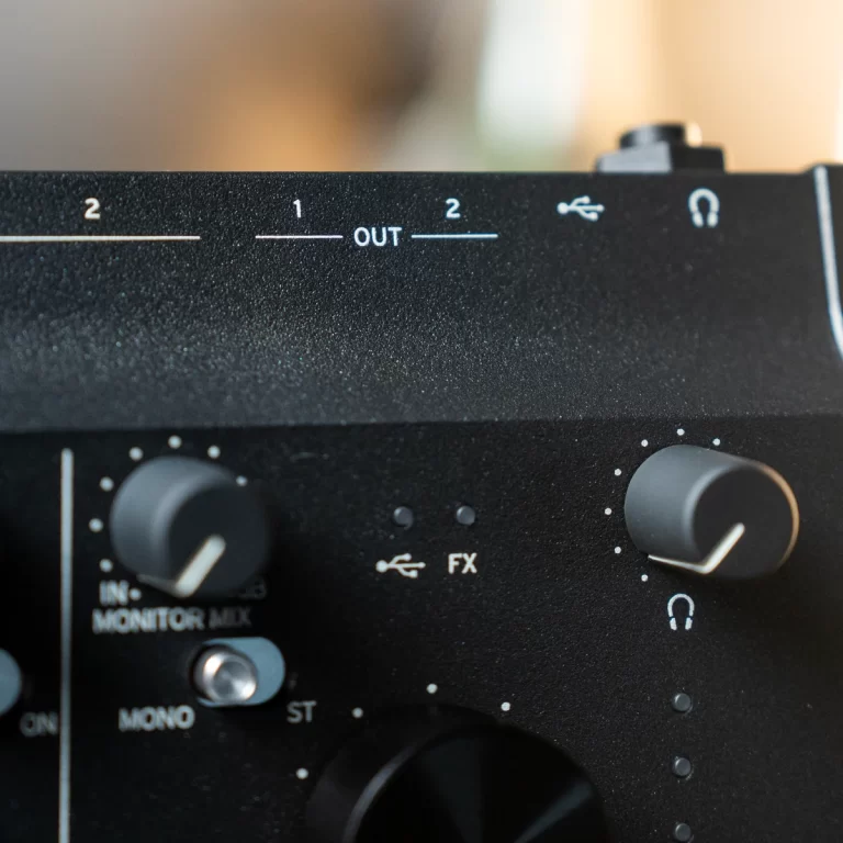 Close-up of a black audio mixer panel showing OUT 1 and OUT 2 indicators, knobs, and a headphone icon, illustrating output routing controls. ขายราคาพิเศษ
