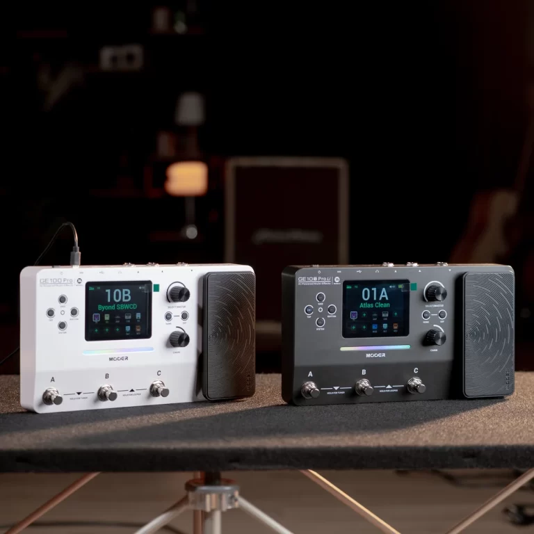 Two Mooer GE100 Pro multi-effects pedals on a table, white left and black right, each with a color display and built-in expression pedal area. ขายราคาพิเศษ