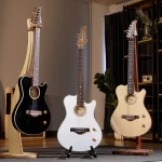 Three electric/acoustic guitars on stands in a showroom: black cutaway on left, white semi-acoustic in center, natural wood cutaway on right with shelving and plant in background ลดราคาพิเศษ