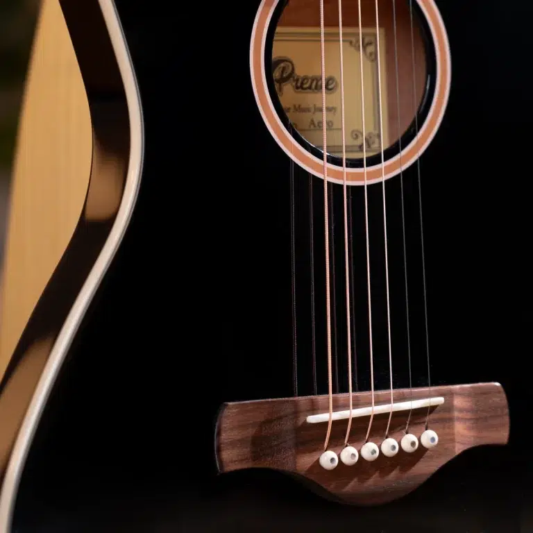 Close-up of a black acoustic guitar, showing strings over the bridge and soundhole on a glossy finish. ขายราคาพิเศษ