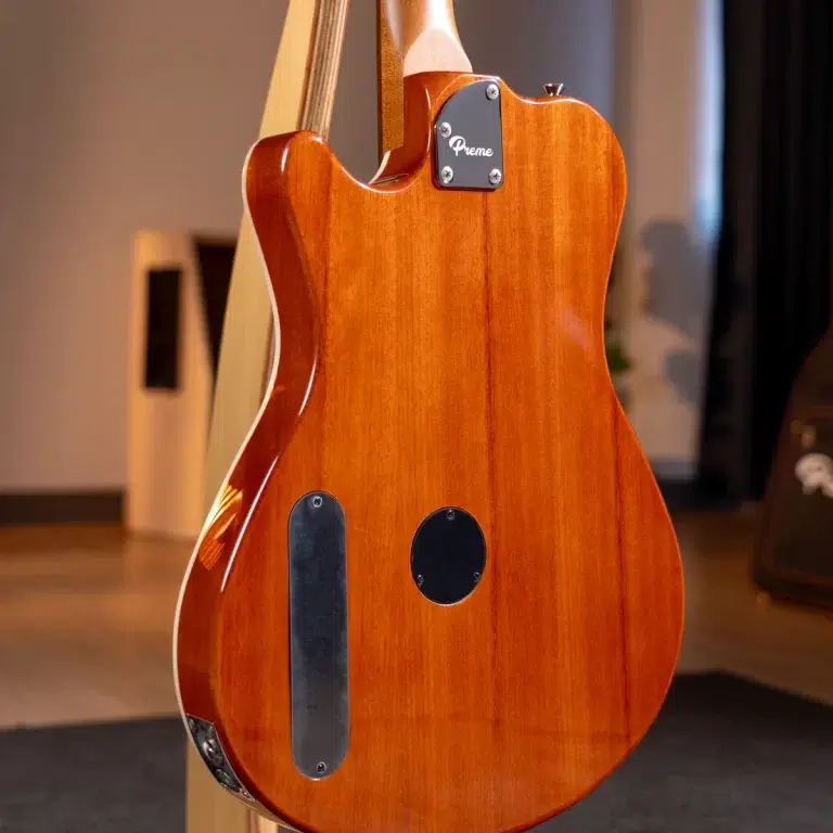 Back view of a glossy orange electric guitar on a stand, with a black neck plate labeled 'Prime' and two black back covers visible on the body. ขายราคาพิเศษ
