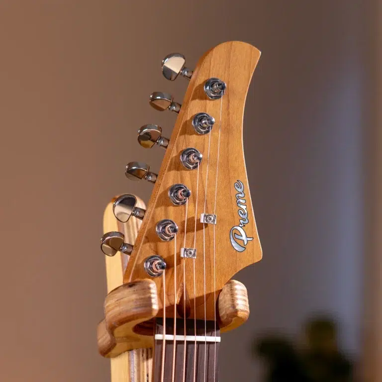 Close-up of a wooden guitar headstock with six chrome tuning pegs and strings visible. ขายราคาพิเศษ