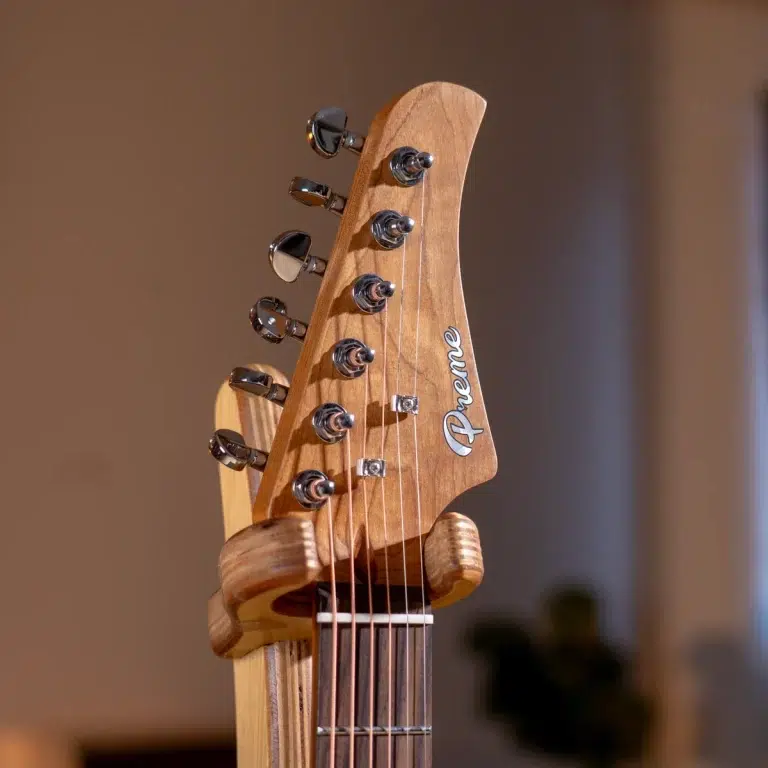 Close-up of a guitar headstock with six tuning pegs and strings, featuring an Avenue logo on the wooden headstock? ขายราคาพิเศษ