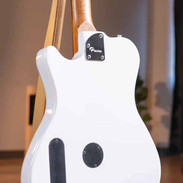Back view of a white electric guitar showing the maple neck, metal neck plate with 'Preme', and glossy body finish in an indoor setting. ขายราคาพิเศษ