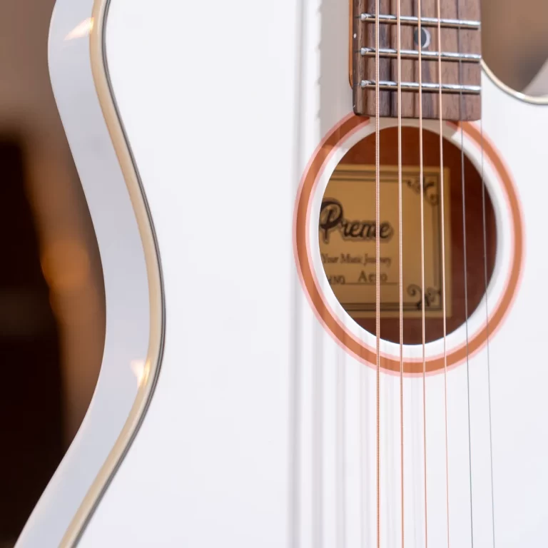 Close-up of a white acoustic guitar focusing on the soundhole and strings, with a gold label inside reading Premier ขายราคาพิเศษ