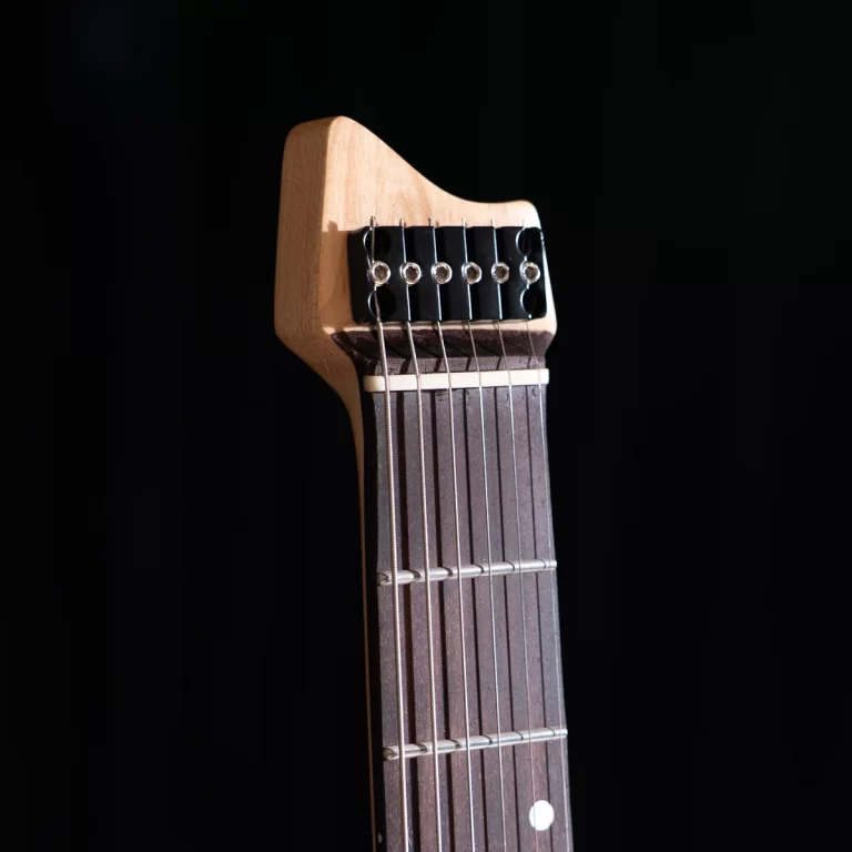 Close-up of a guitar headstock with six tuning pegs and strings on a dark background. ขายราคาพิเศษ