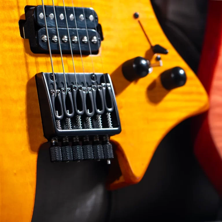 Close-up of an orange electric guitar showing the bridge, strings, and control knobs on a wooden body ขายราคาพิเศษ