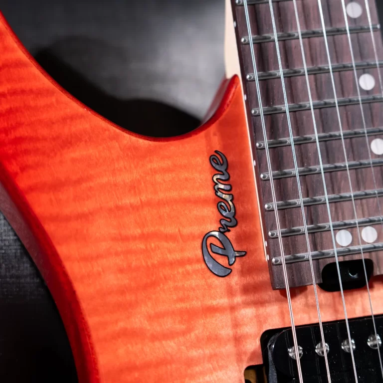 Close-up of an orange electric guitar body with a curved cutaway, showing the Danelectro logo and the neck with tuning pegs and strings still in place. ขายราคาพิเศษ