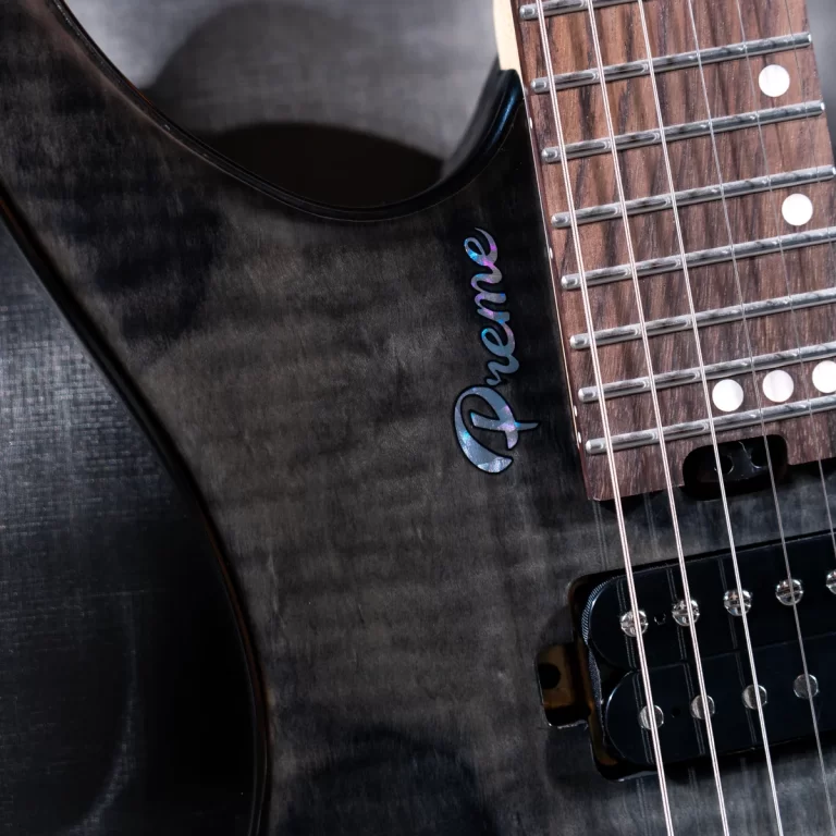 Close-up of a dark electric guitar body with a blue iridescent Fender logo and strings over a maple fretboard. ขายราคาพิเศษ