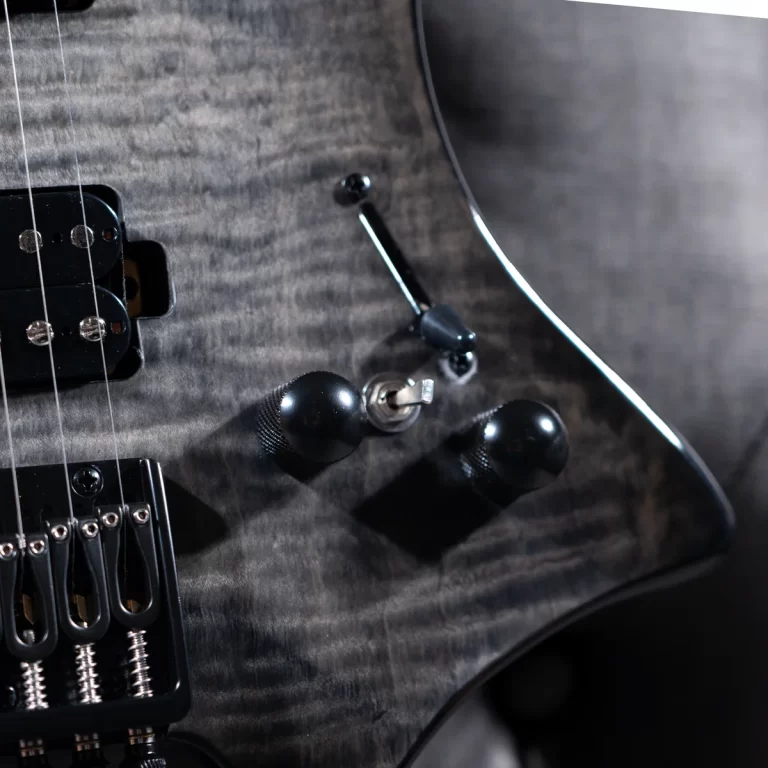 Close-up of a dark quilted electric guitar showing the bridge, pickup, and control knobs. ขายราคาพิเศษ
