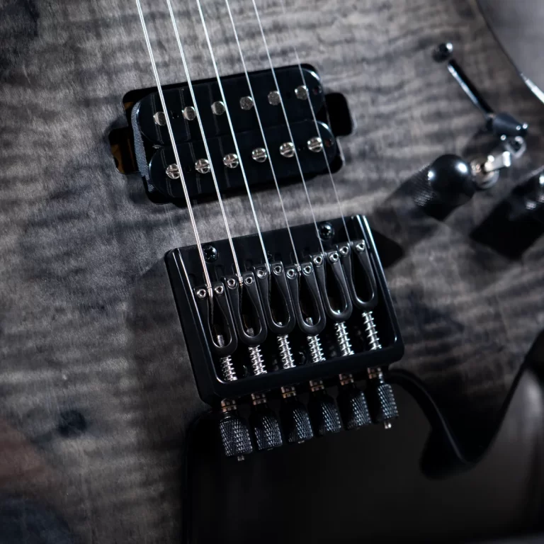Close-up of a black electric guitar bridge with six tremolo saddles and steel strings on a dark wood body, showing the pickups nearby. ขายราคาพิเศษ