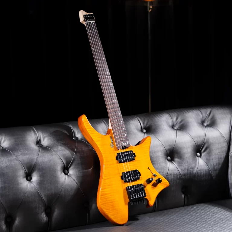 Bright orange electric guitar with two humbuckers resting on a tufted black sofa against a dark background. ขายราคาพิเศษ