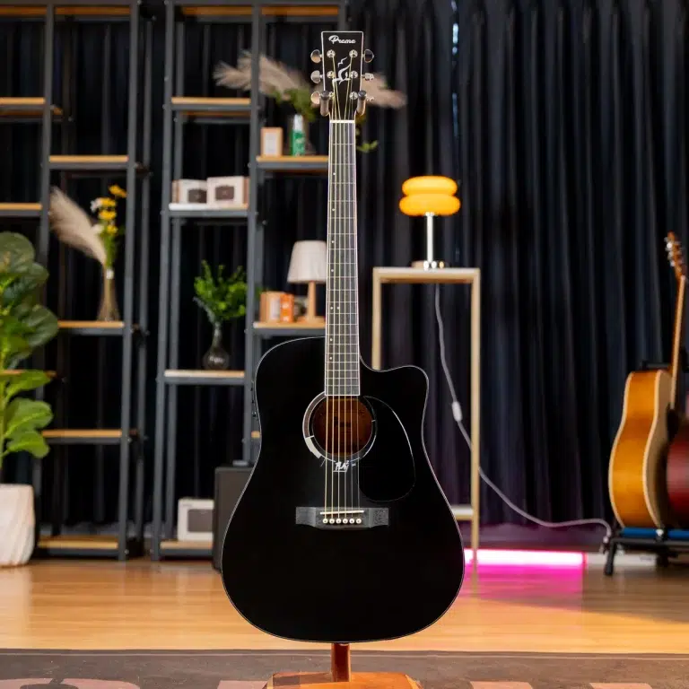 Black acoustic guitar on a stand in a showroom with shelves and other guitars in the background for context. ขายราคาพิเศษ