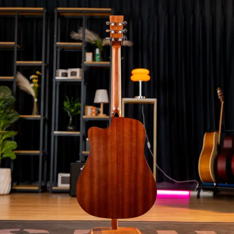 Back view of a wooden acoustic guitar on a stand in a studio showroom, with shelves and another guitar in the background ขายราคาพิเศษ