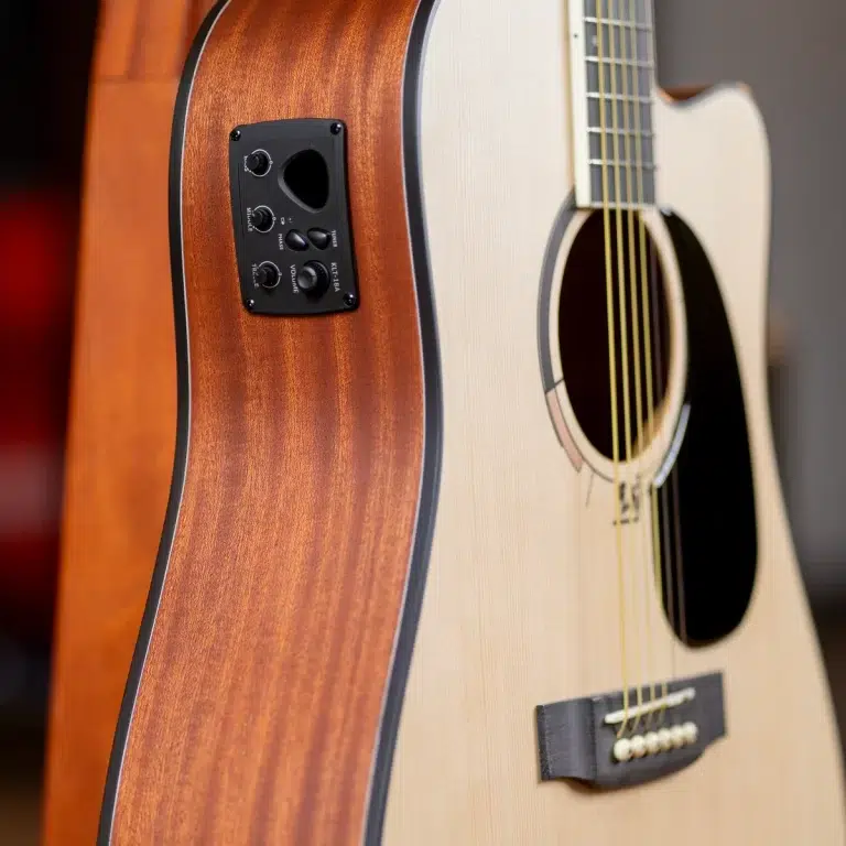 Close-up of an acoustic guitar showing the wooden body, sound hole, and a black control panel with knobs on the side. ขายราคาพิเศษ