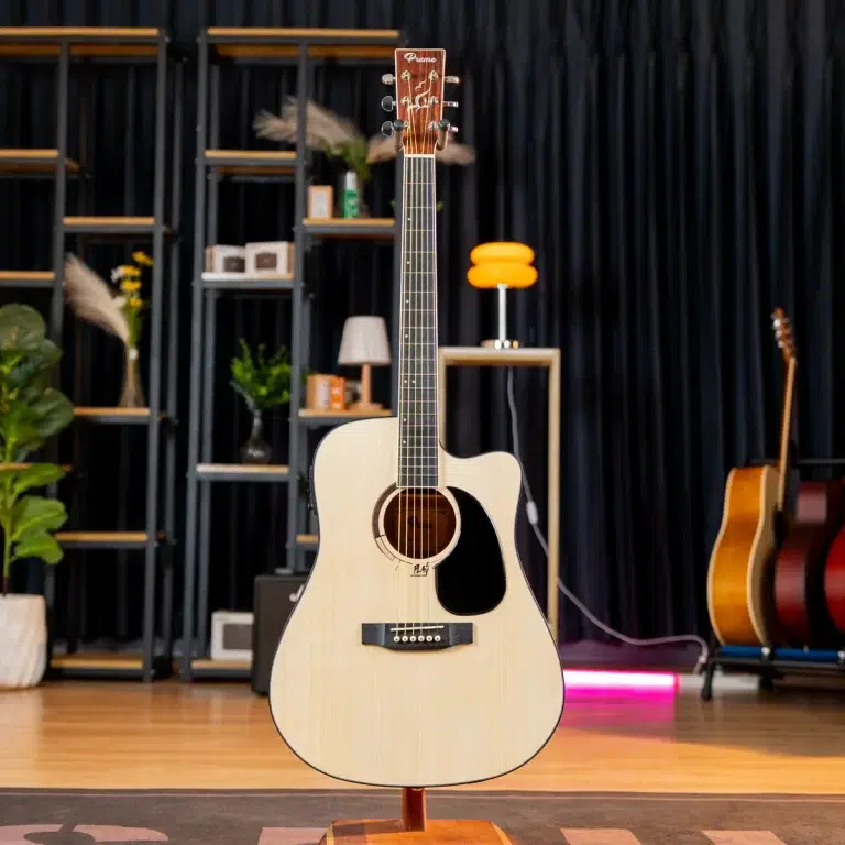 Center-stage acoustic guitar on a stand in a music studio/showroom with shelves and other instruments in the background, natural finish. ขายราคาพิเศษ