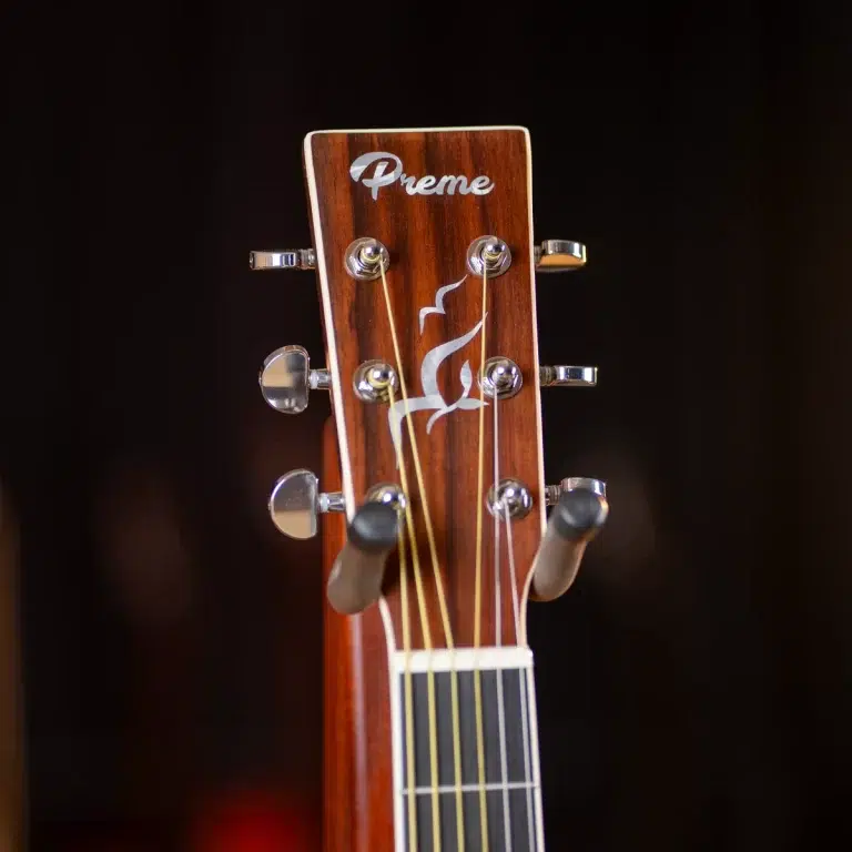 Wooden guitar headstock with six tuning pegs, decorative white inlay, and brand name 'Preme' on a dark background ขายราคาพิเศษ