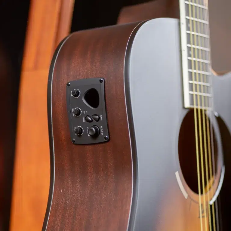 Close-up of a brown acoustic guitar body with a black built-in preamp panel featuring knobs for tone, volume, and other controls on the side of the guitar. ขายราคาพิเศษ