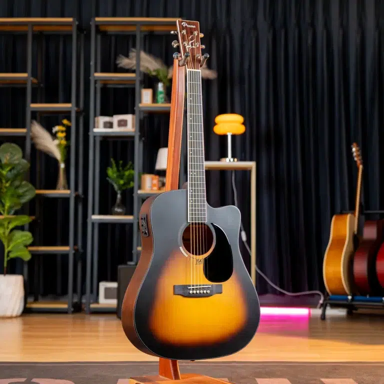 Sunburst acoustic guitar on a stand in a music studio showroom, with shelves and other guitars in the background. ขายราคาพิเศษ