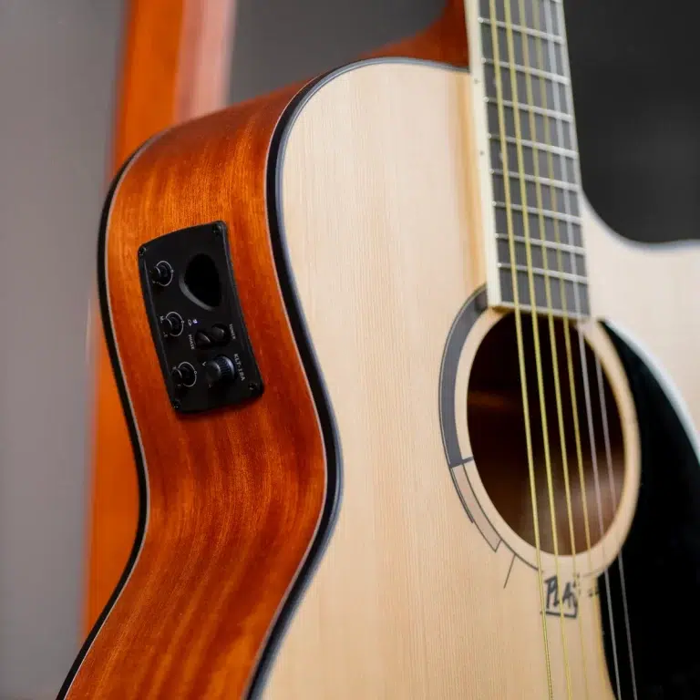 Close-up of an acoustic guitar with a sunburst back, natural top, and built-in electronics panel on the side. ขายราคาพิเศษ