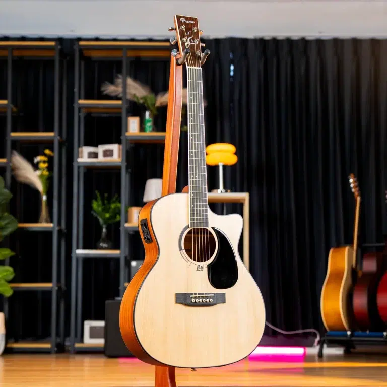 Acoustic guitar on a stand in a showroom with shelves and other guitars in the background ขายราคาพิเศษ