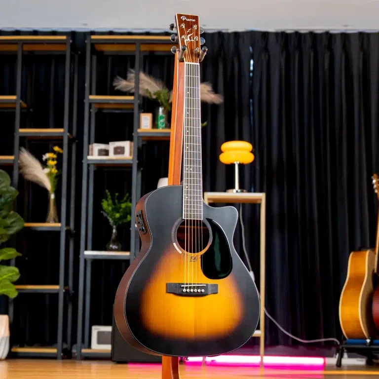 Sunburst acoustic guitar on a stand in a stage-like setting with shelves and a black curtain backdrop. ขายราคาพิเศษ