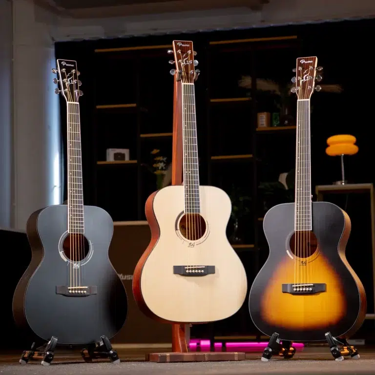 Three acoustic guitars on stands in a showroom, featuring dark, natural, and sunburst finishes from left to right. ขายราคาพิเศษ