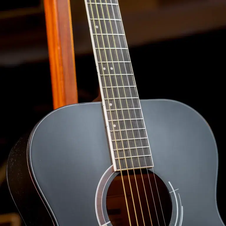 Close-up of a gray acoustic guitar from the body to the neck, showing six strings and frets. ขายราคาพิเศษ