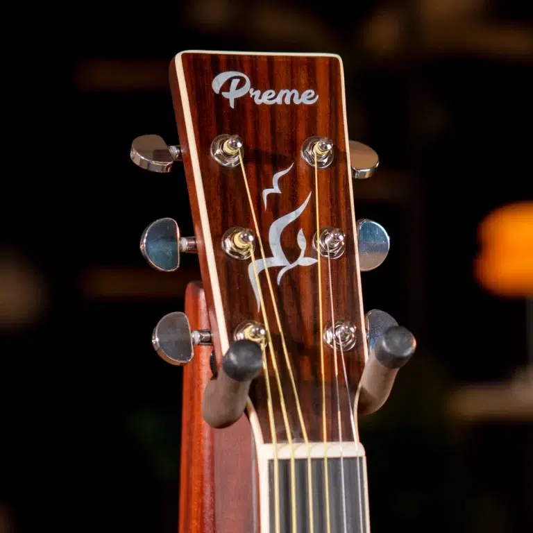 Close-up of a wooden guitar headstock with tuning pegs and decorative flame inlay ขายราคาพิเศษ