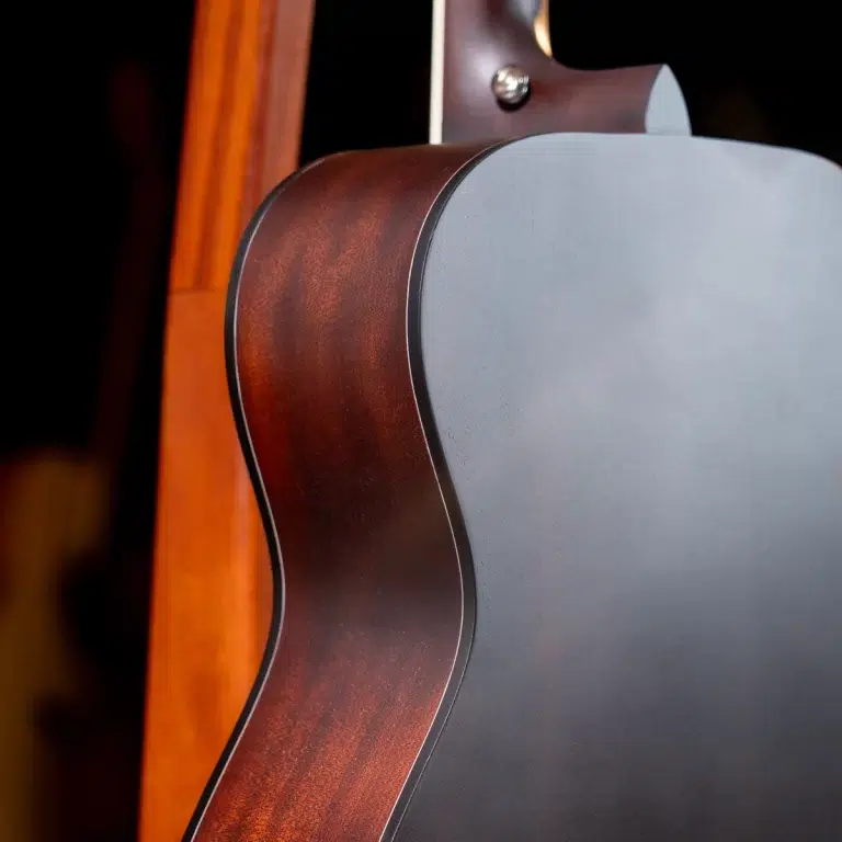 Close-up of an acoustic guitar showing the brown wooden rim and gray back, highlighting the curved body edge. ขายราคาพิเศษ