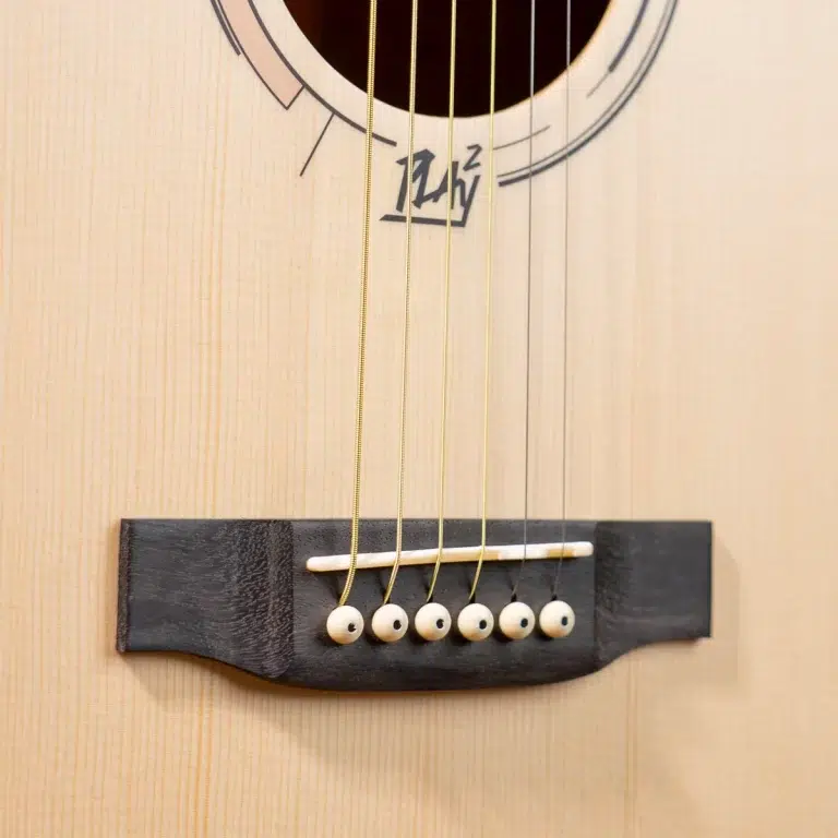 Close-up of a guitar's bridge with six steel strings and white pins on a light wood body. ขายราคาพิเศษ