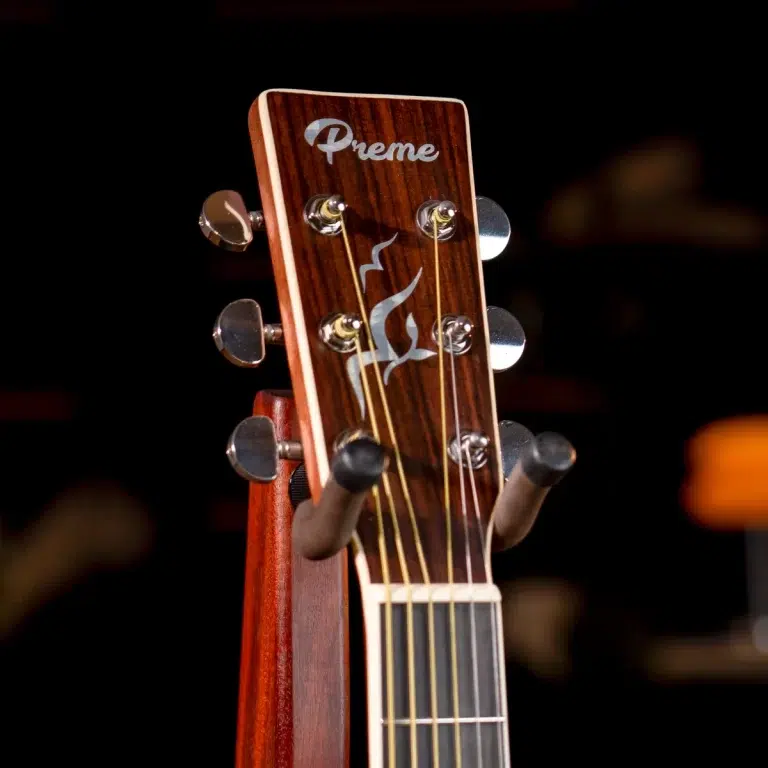 Close-up of a wooden guitar headstock with six tuning pegs and the 'Preme' logo on the face of the headstock. ขายราคาพิเศษ