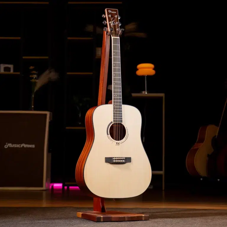 Acoustic guitar on a wooden stand center stage, white top and natural wood sides, with warm stage lighting and other equipment visible in a dark background. ขายราคาพิเศษ