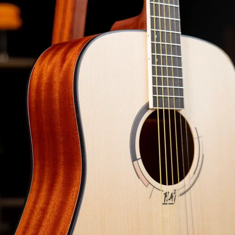 Close-up of a light-colored acoustic guitar with a sunburst back, showing strings and the sound hole ขายราคาพิเศษ