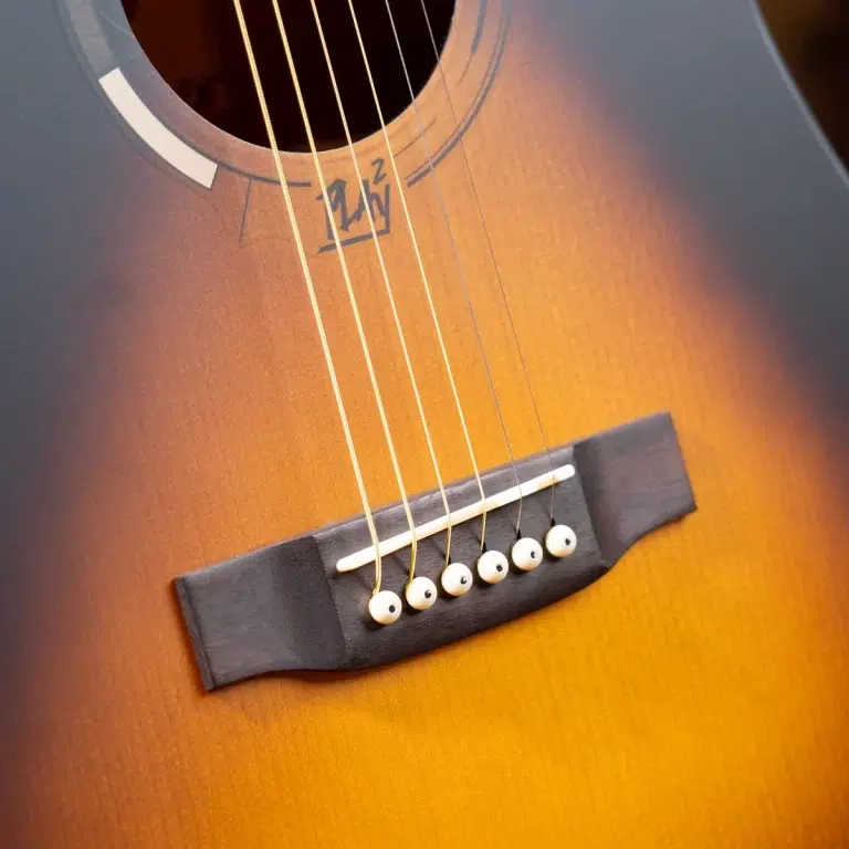 Close-up of an acoustic guitar showing the bridge, strings, and sunburst wood grain near the soundhole. ขายราคาพิเศษ