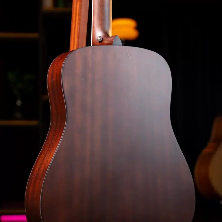 Rear view of a polished brown acoustic guitar with a curved body, showing the dark back and reddish sides against a dark background. ขายราคาพิเศษ